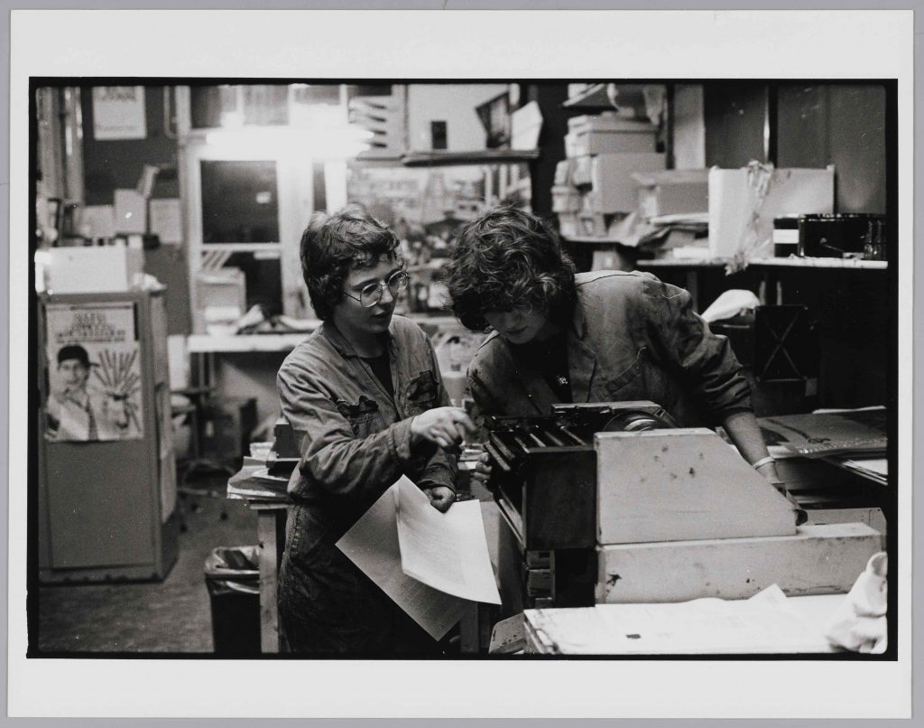 zwart-wit foto met 2 vrouwen die kijken wat er uit een drukpers komt